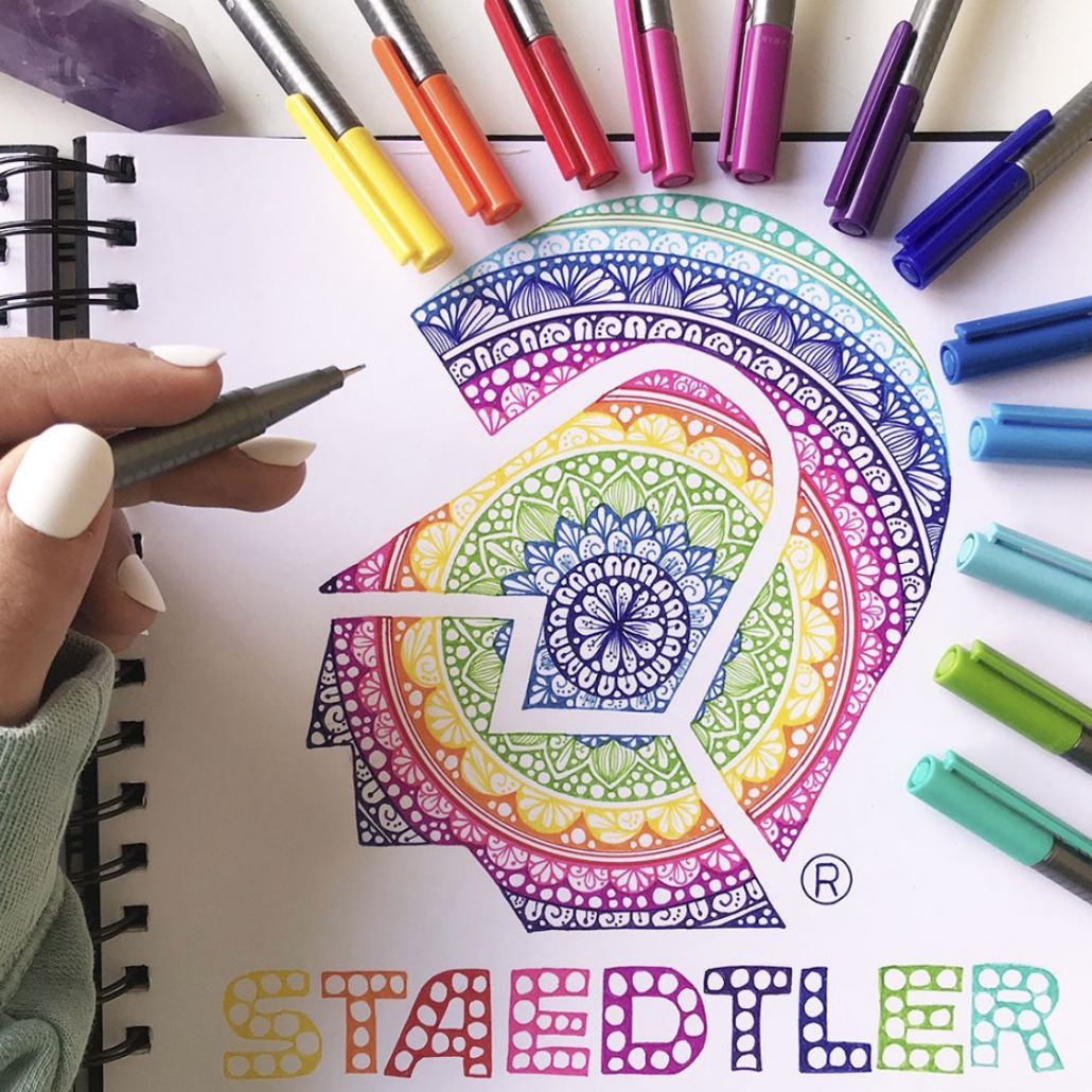 Scatto emozionale di una mano che colora un disegno vivido con matite Staedtler, evidenziando la qualità del tratto.